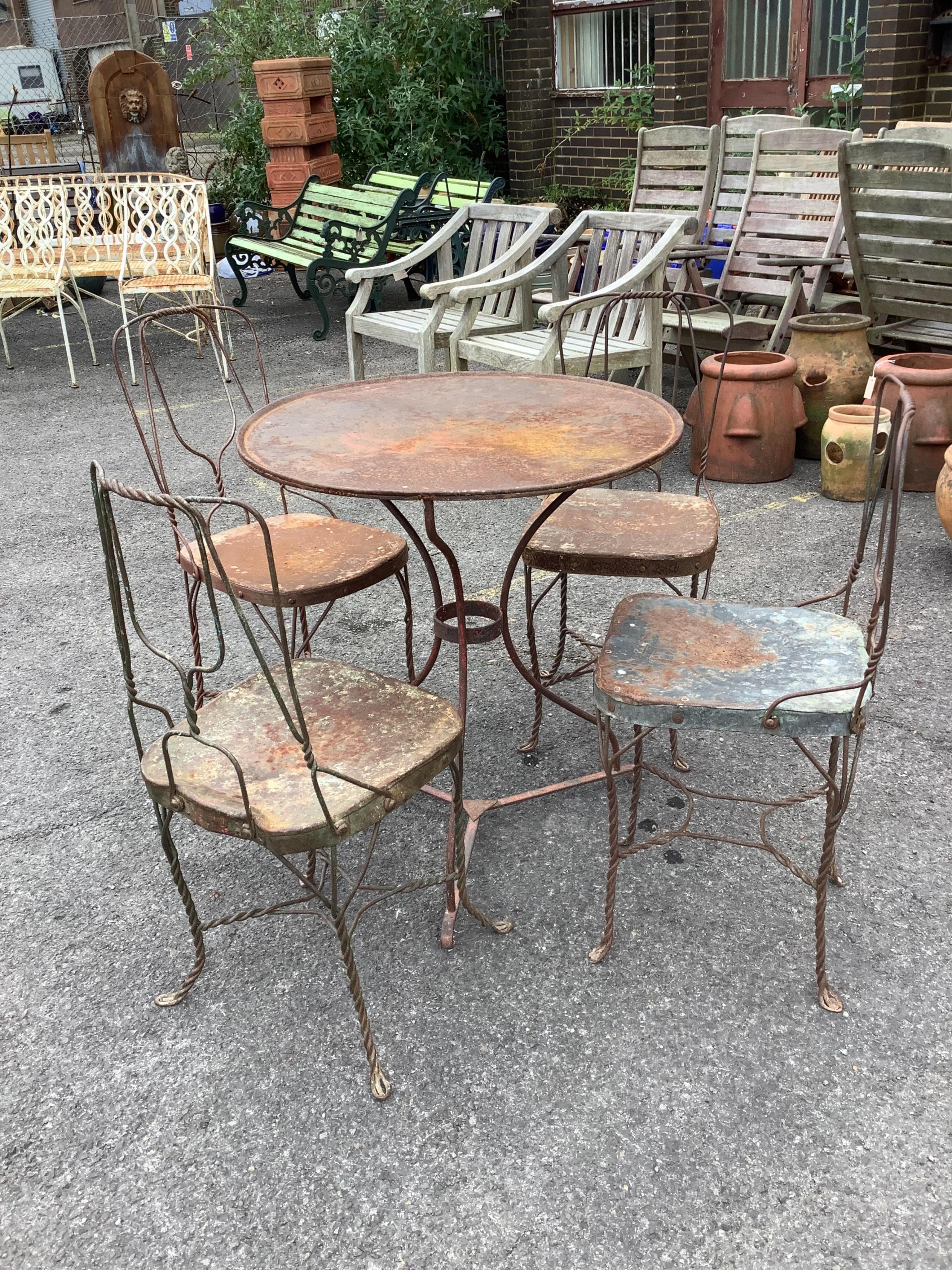 An early 20th century wrought iron garden table, diameter 70cm, height 75cm and four chairs. Condition - fair